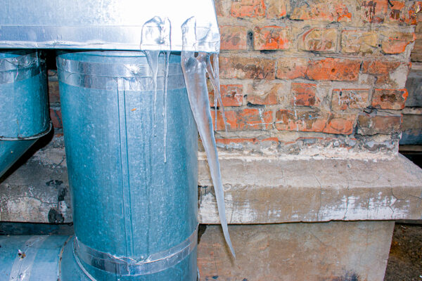 How to Winterize Your Above Ground Plumbing System, Icicles and ice frozen iron downpipe. Frozen water and metal pipe, winter time concept. Close-up